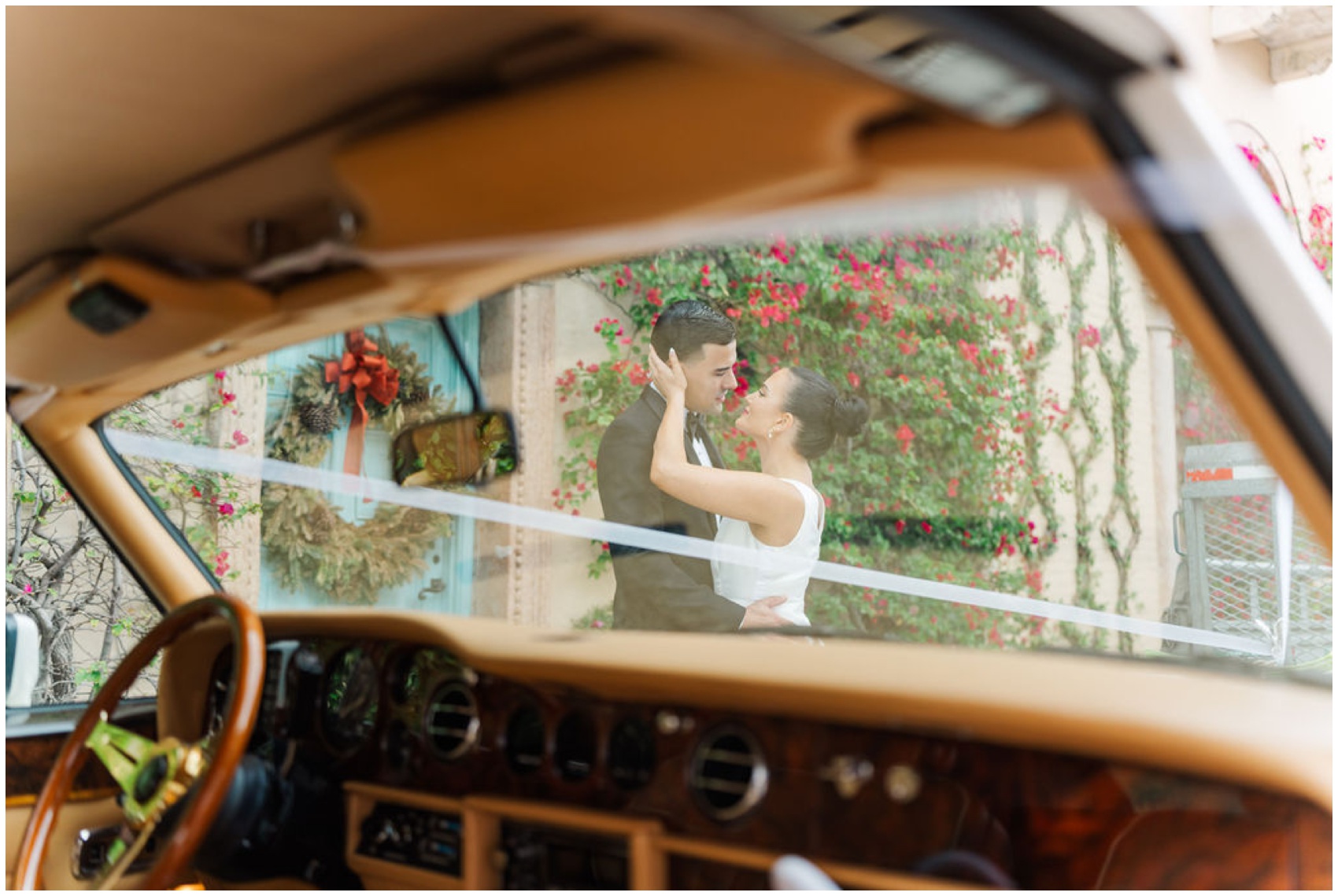 A peak through a car's windshield to newlyweds kissing