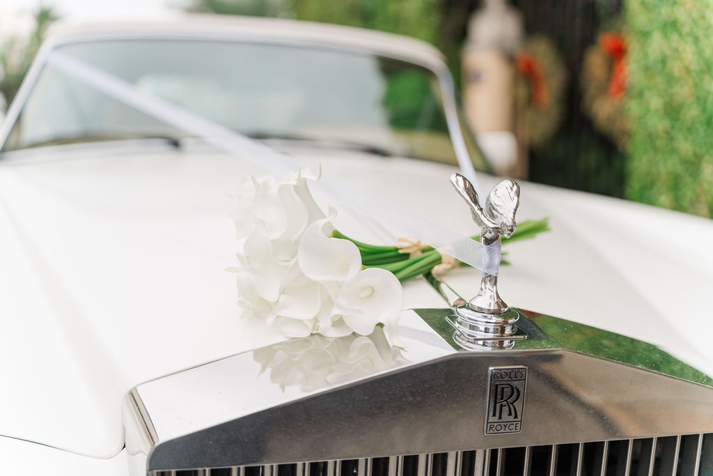 Details of white flowers sitting on the hood of a vintage Rolles Royce outside one of the wedding venues in west Palm Beach