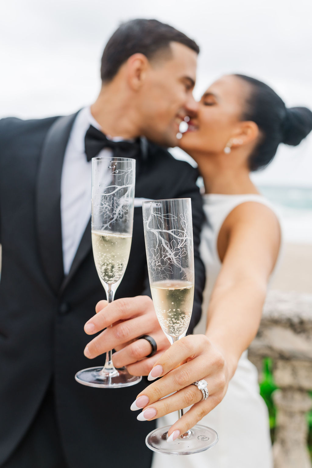 Newlyweds kiss while showing off engraved champagne glasses