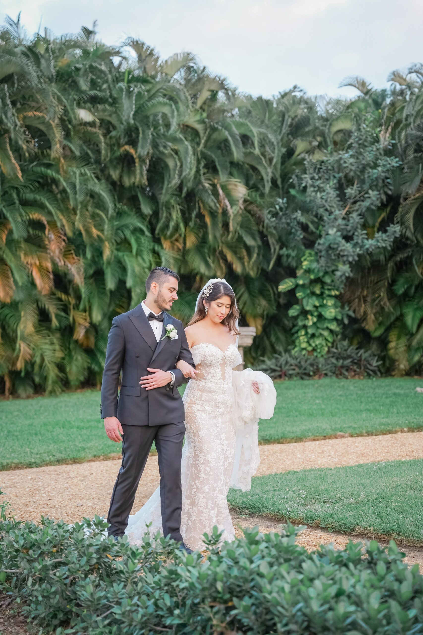 Newlyweds share a quiet walk in a garden with arms locked