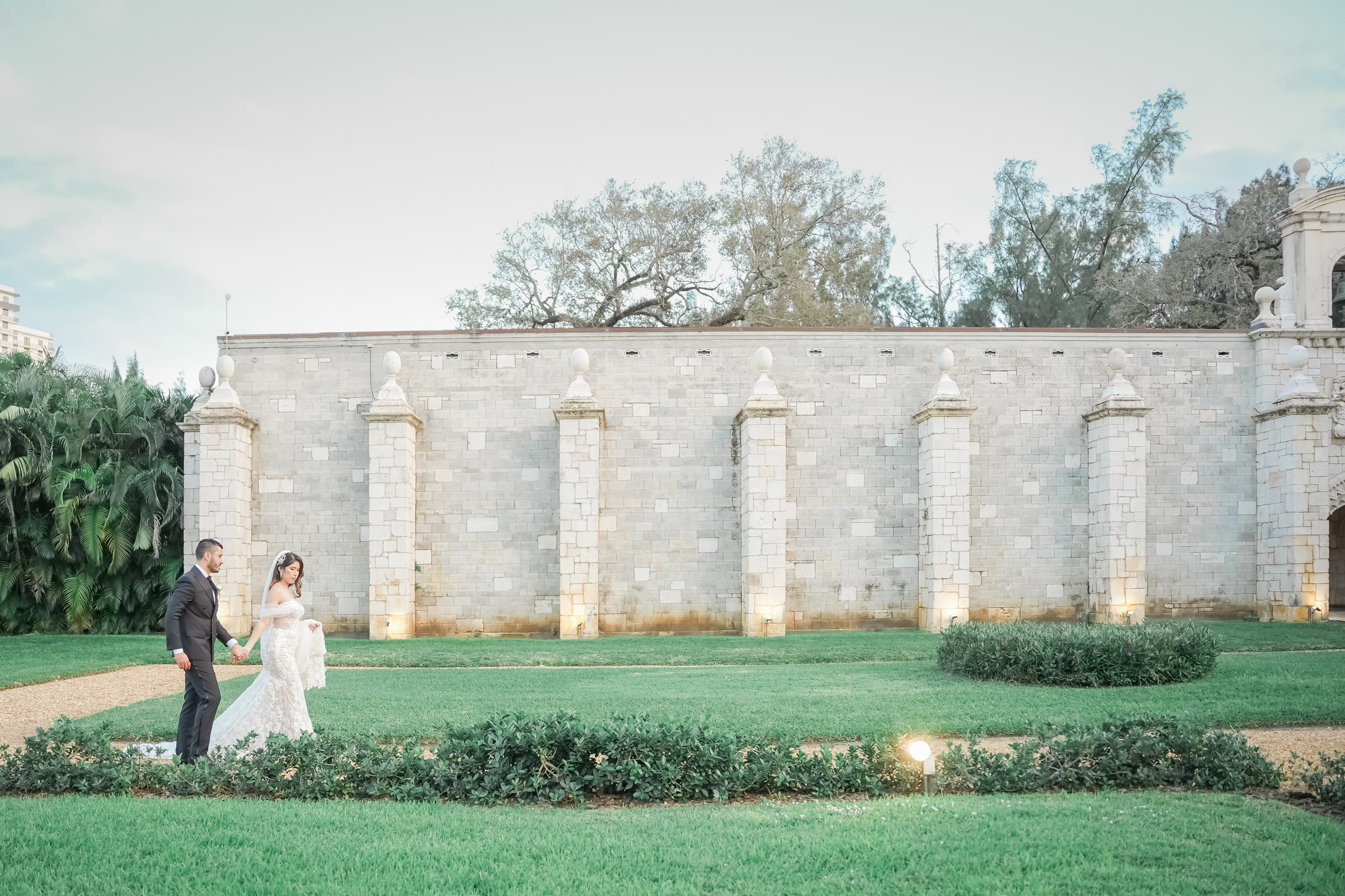 Newlyweds walk a garden path holding hands