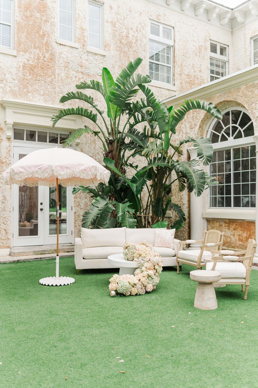 A look into a patio with turf set up with a couch and chairs at one of the european style wedding venues in florida