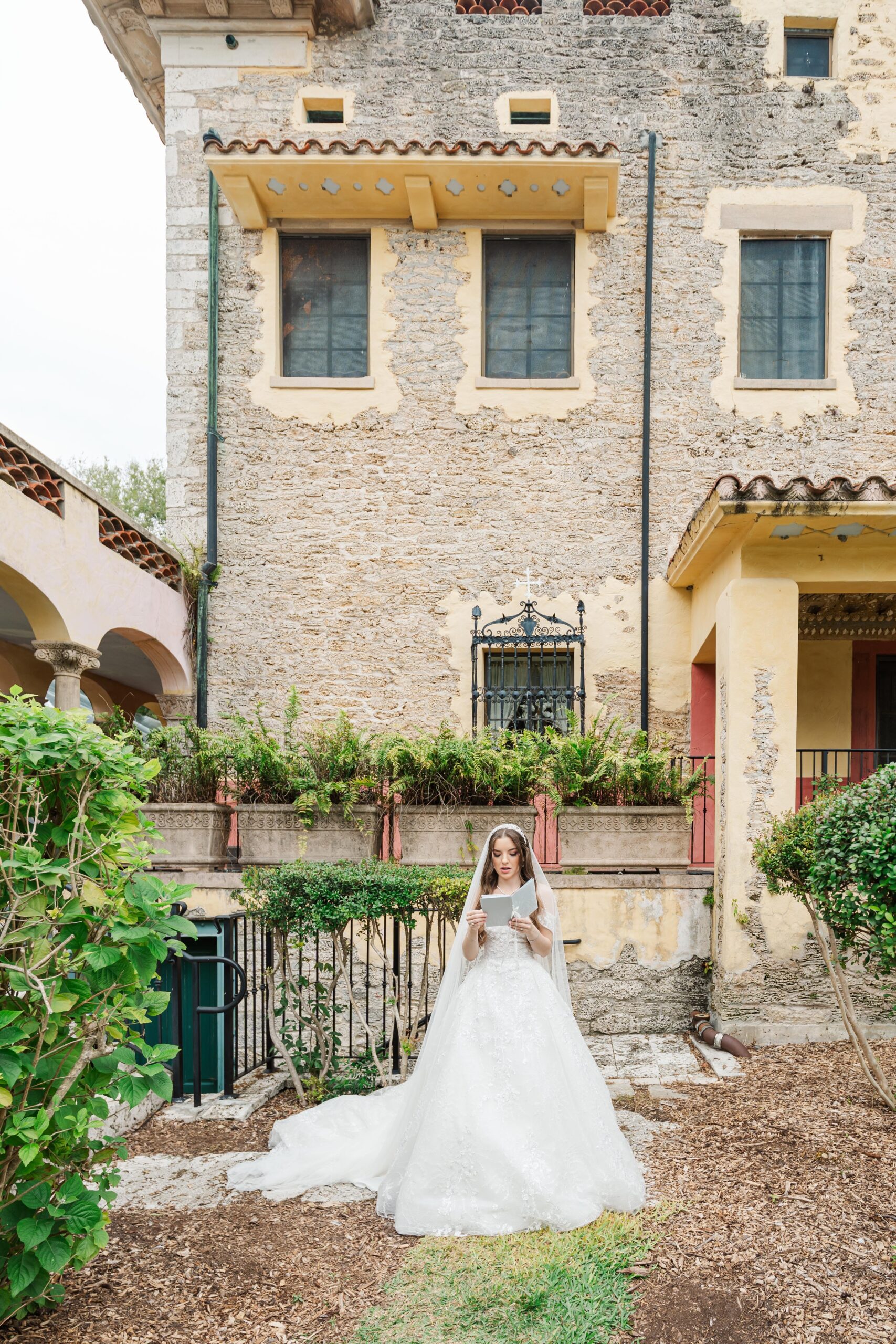 A bride reads her letter while standing in the garden of one of the luxury wedding venues in miami