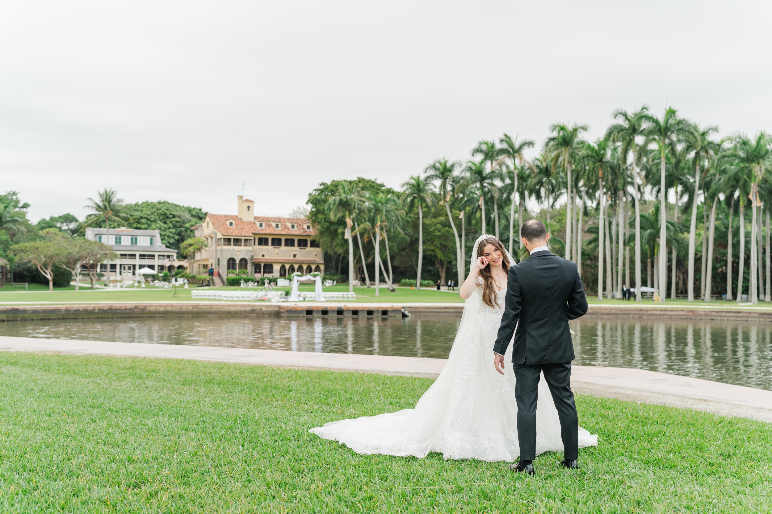 A bride cries while standing by the water in a lawn at one of the luxury wedding venues in miami