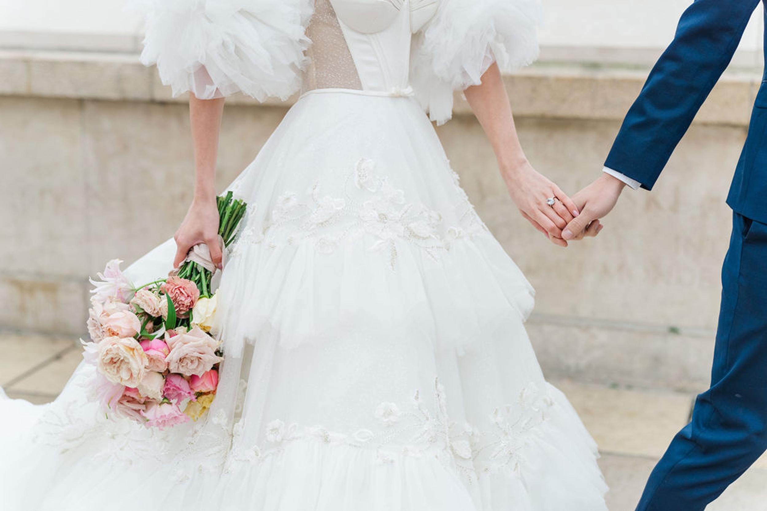 Details of newlyweds walking and holding hands with a colorful bouquet